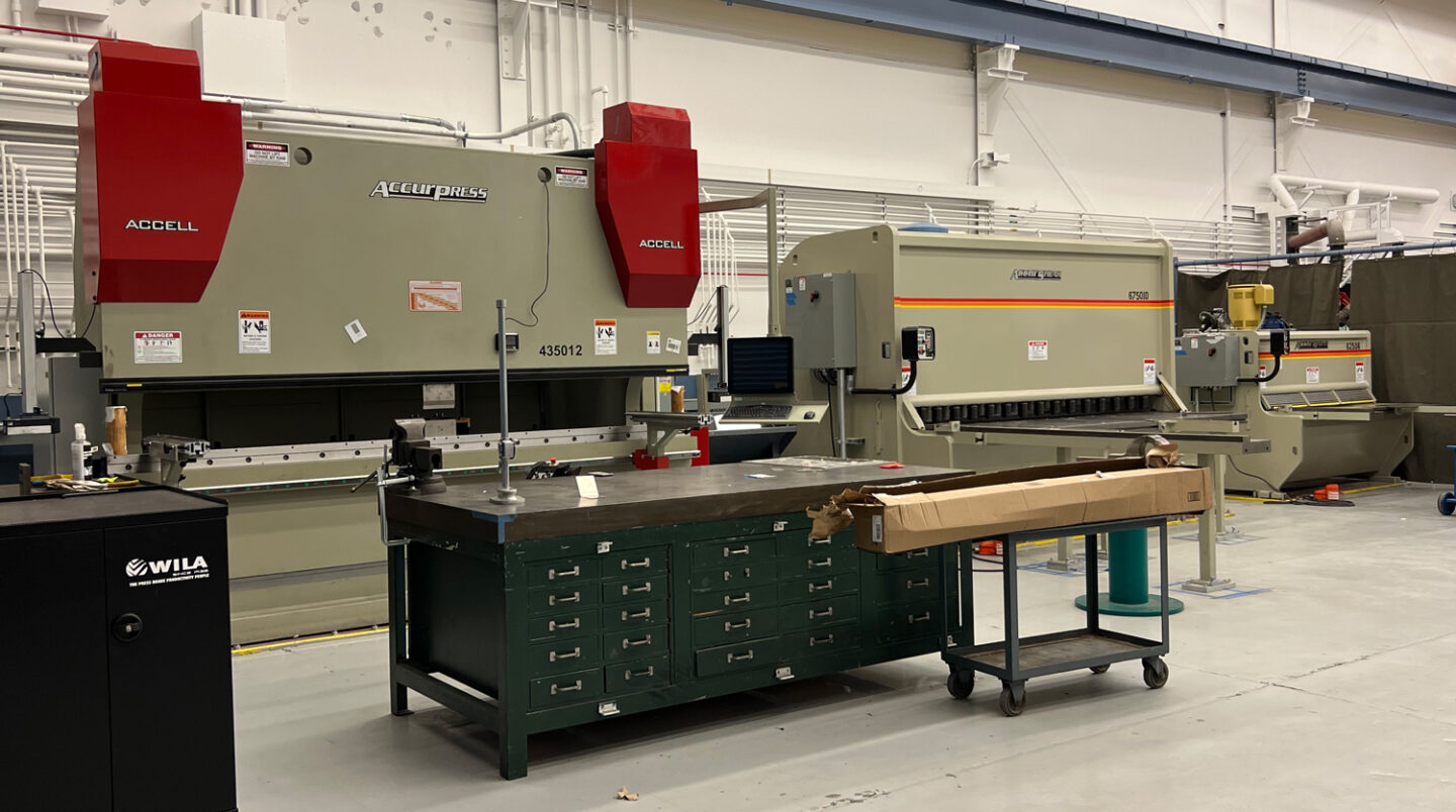 Machine shop interior with heavy-duty sheet metal forming equipment including a press brake and precision cutting shears