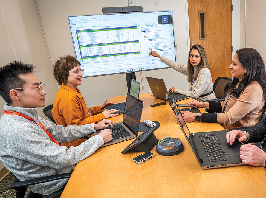 People with laptops in a conference room discussing a presentation.