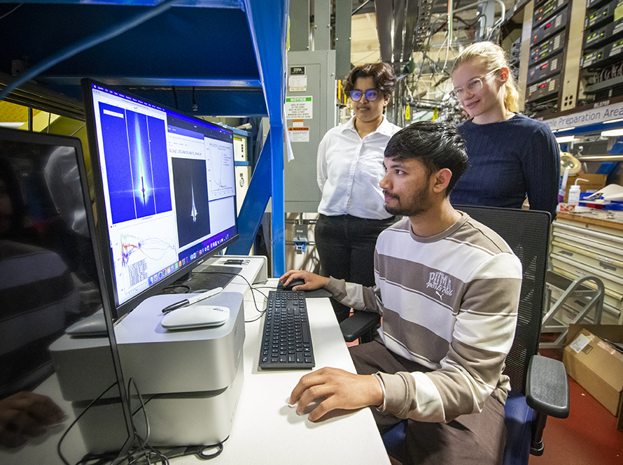 Intern conducts research at beamline 7.3.3 as two mentors observe.