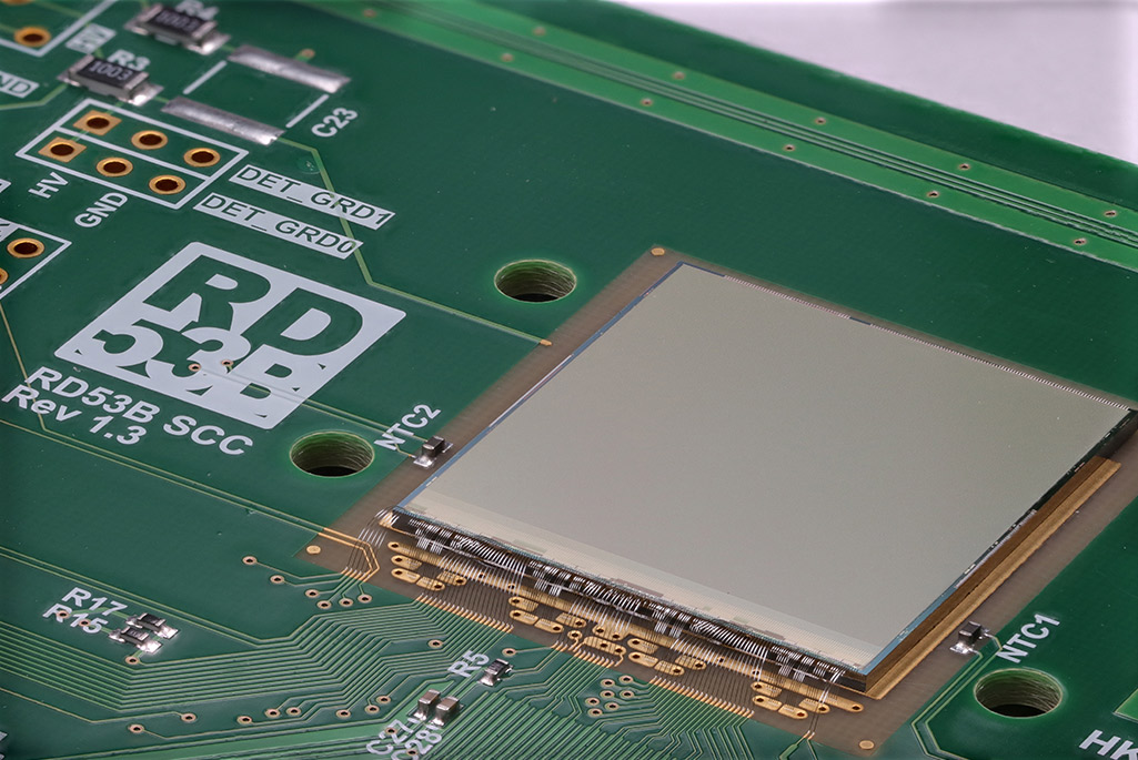 Close-up of silicon readout chip with bond wires mounted on green circuit board