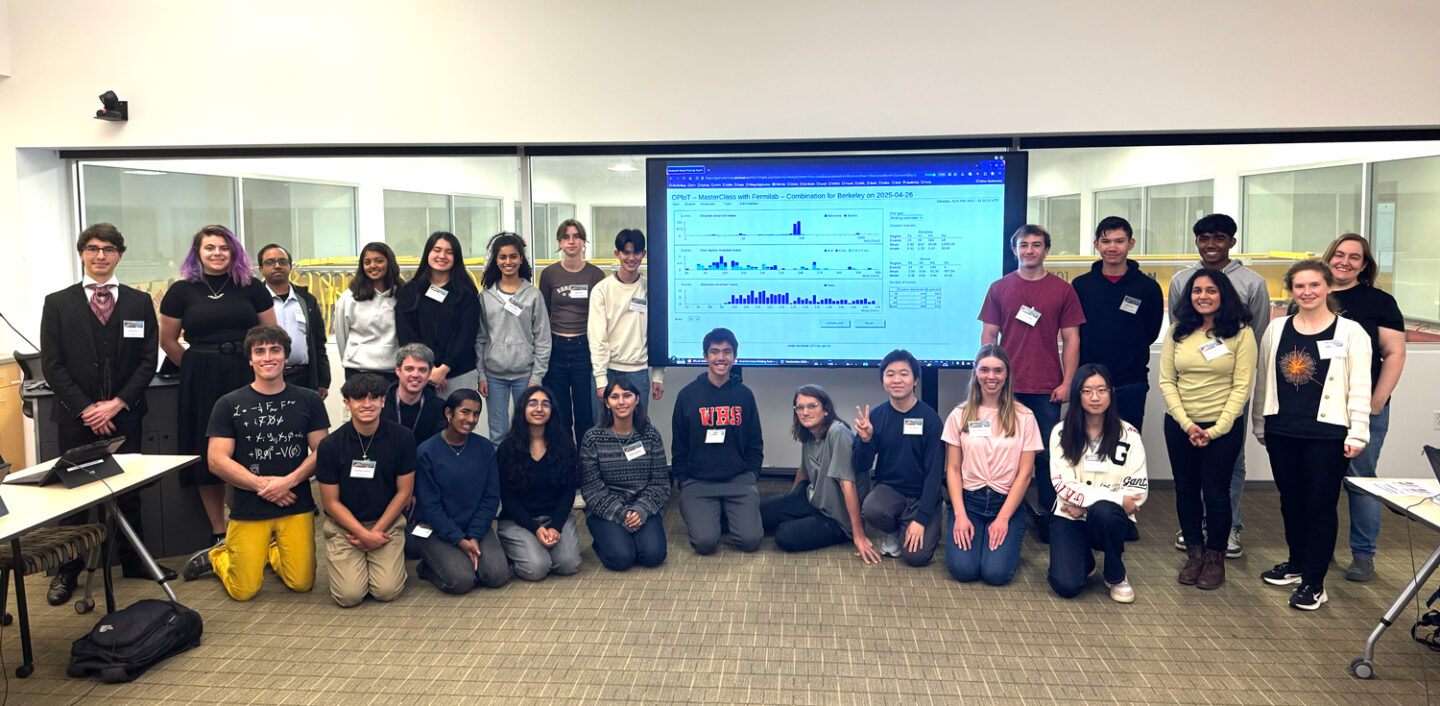 ATLAS students and instructors pose around a large flat panel display with data