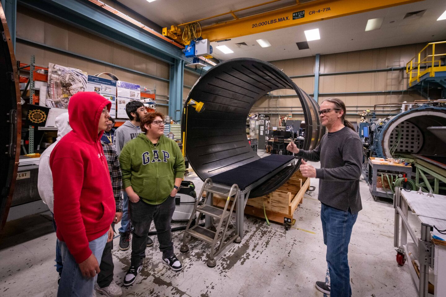 An Engineering technical associate showcasing the carbon fiber support structures to high school students