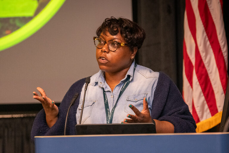 Faith Dukes speaks to students and staff gathered in the Building 50 Auditorium.