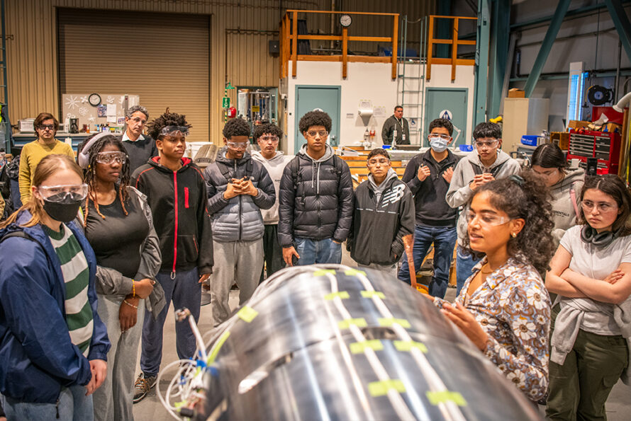 Engineer demonstrates a large cylindrical superconducting magnet to high school students during a STEM outreach event