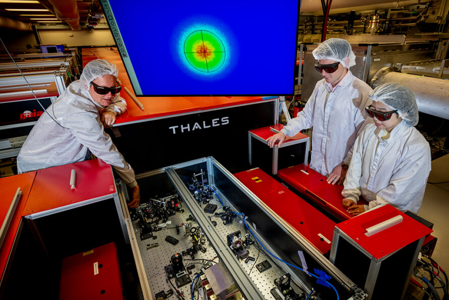 Three researchers aligning precision optics on a laser system