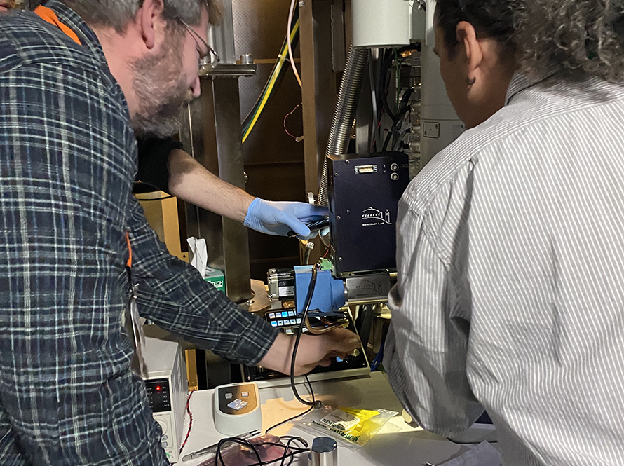 Two researchers working with a radiation-hardened camera system mounted on laboratory equipment.