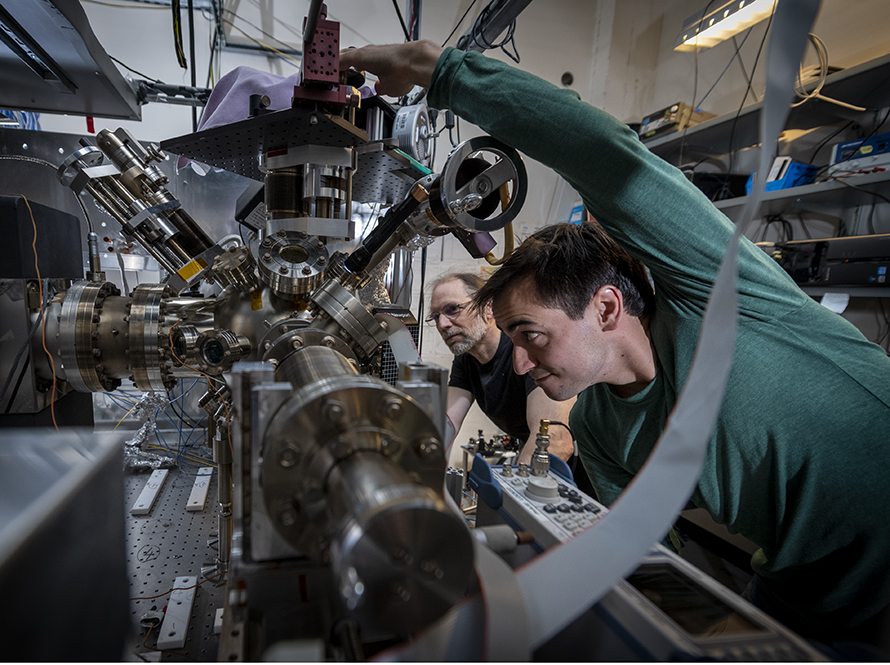 Student and professor adjust settings on a vacuum apparatus for trapping ions at Häffner’s laboratory.