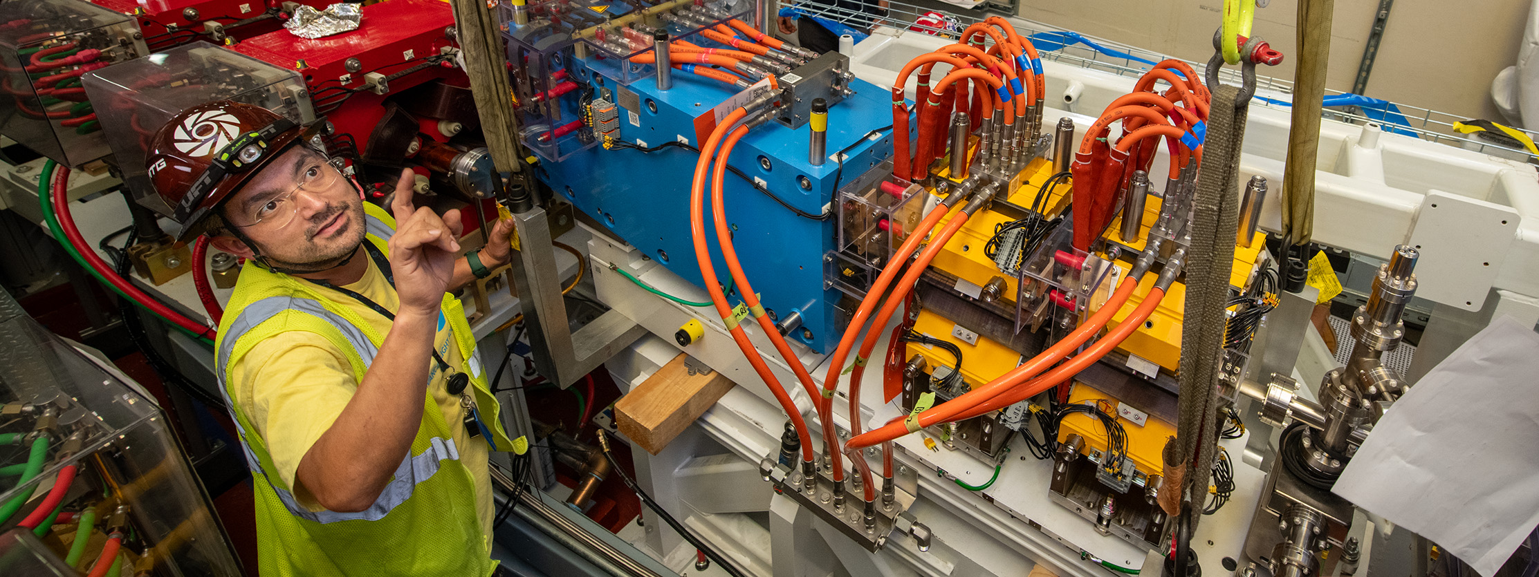 Worker in hard hat moves heavy equipment with a hoist.