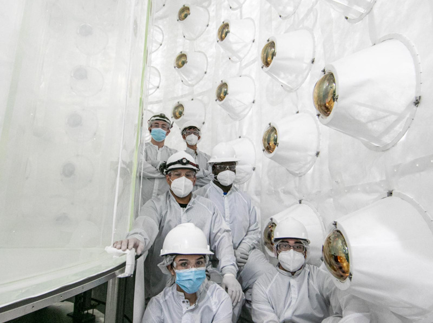 A group in full PPE posing in front of equipment used for LUX-ZEPLIN.