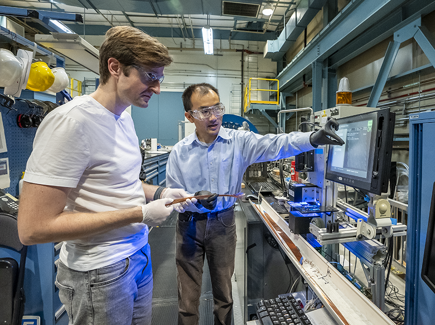 Two researchers in safety glasses working together at a laboratory equipment station