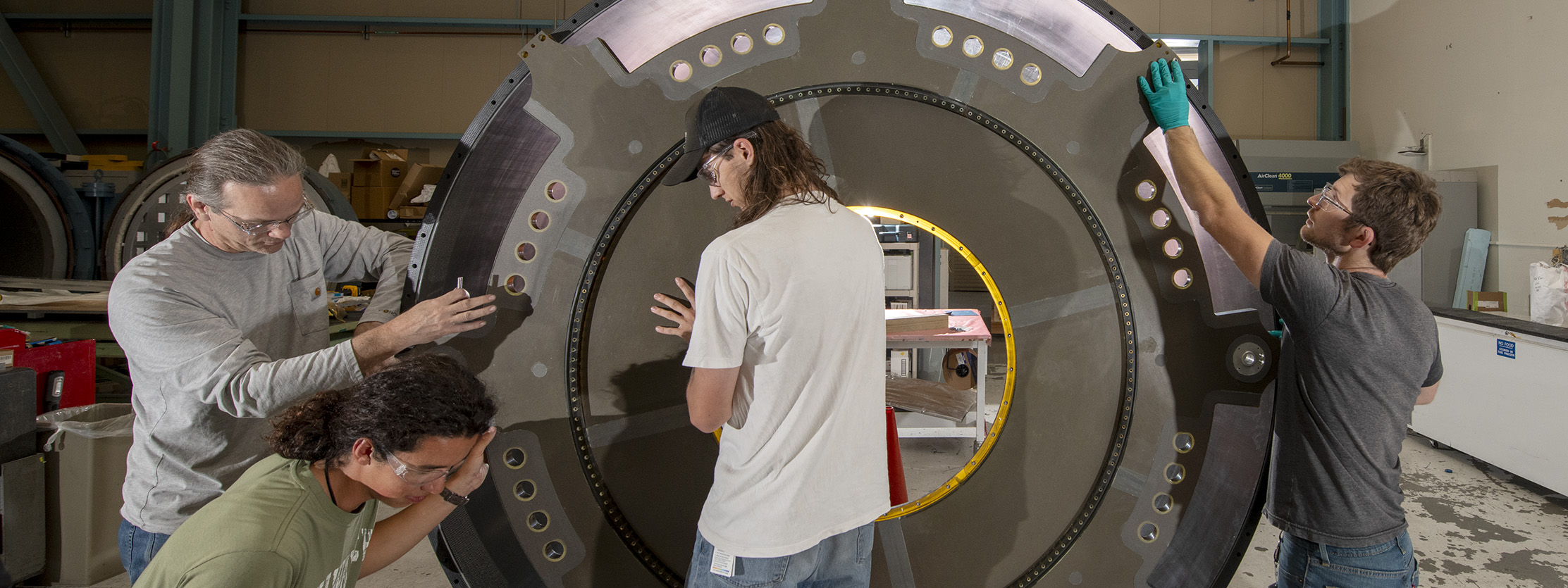Part of the ATLAS Detector carbon fiber cylinder is lifted into place as it is being assembled.