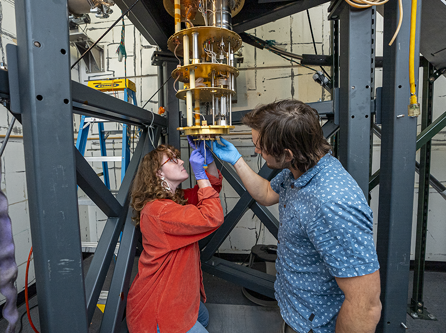 Two engineers working on installing a component for TESSERACT.