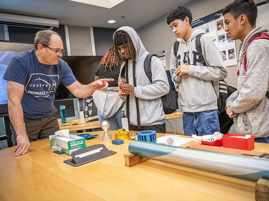 Machinist presenting to high school students in workshop.