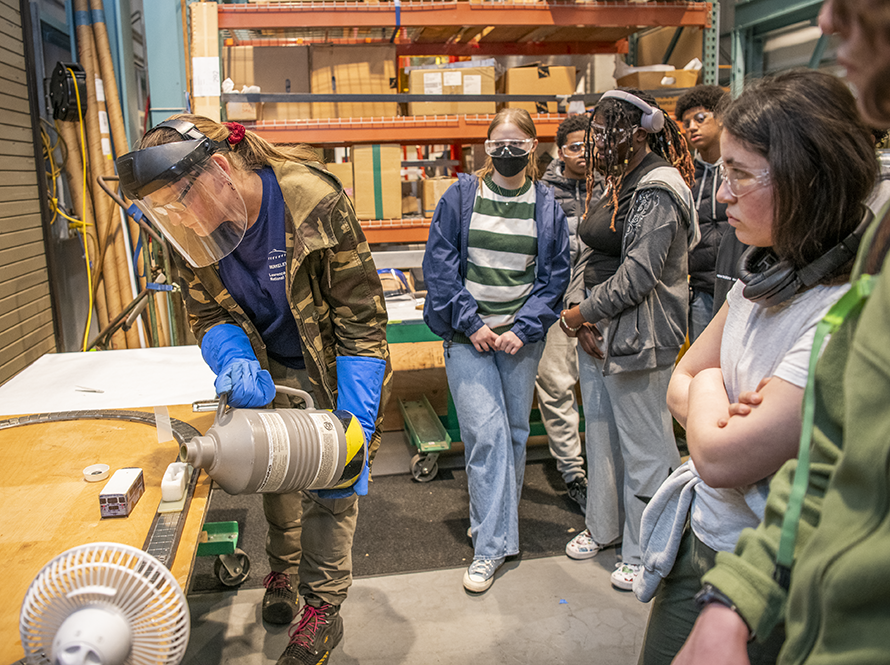 High school students watching maglev train demonstration.