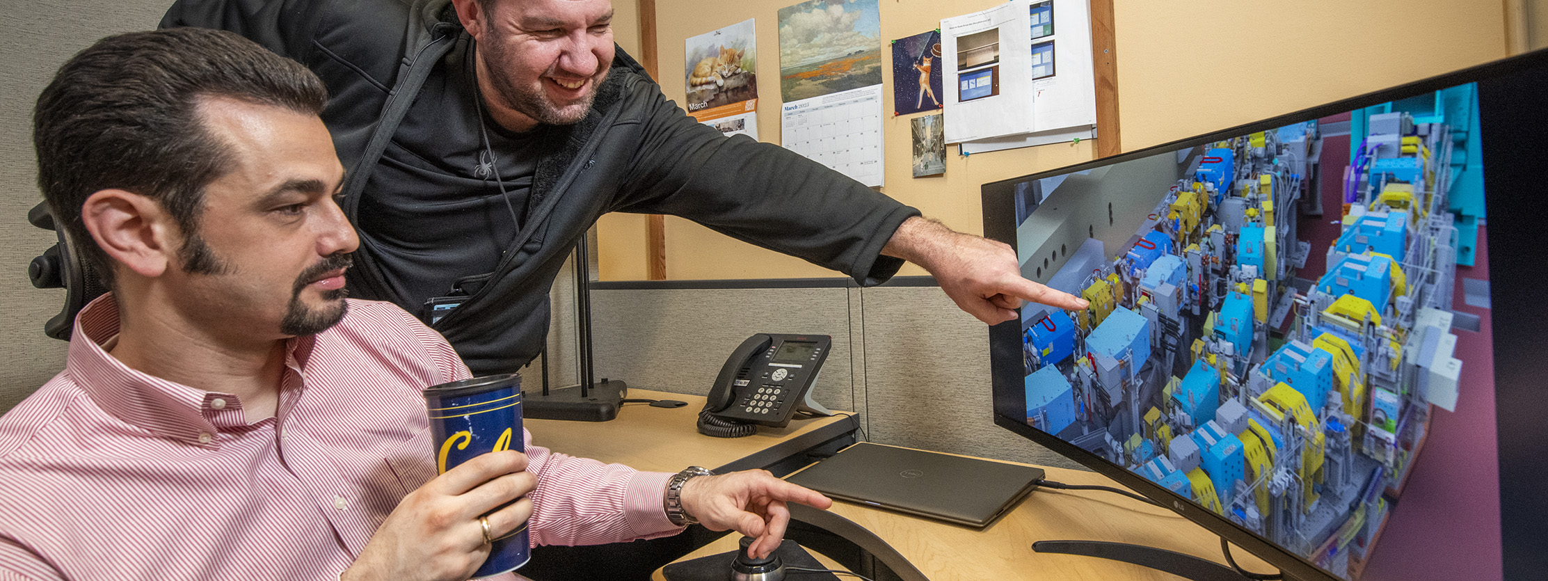 Engineers review image on computer monitor.