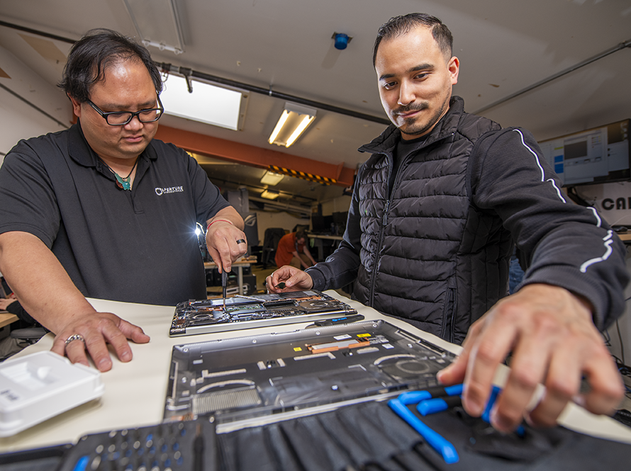 Two Desktop Support staff repairing laptop computers.