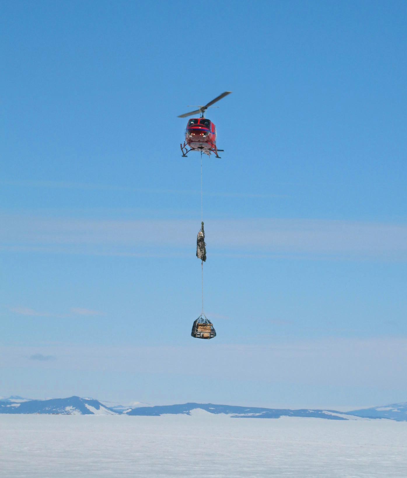 Helicopter carrying load over snow