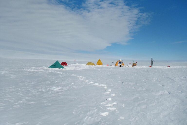 Field camp on ice shelf in Antarctica showing several tents across the snowy landscape