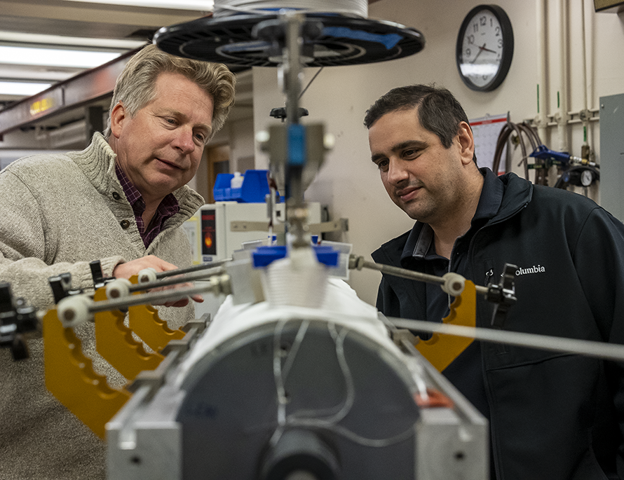 Colleagues examine a piece of lab equipment.