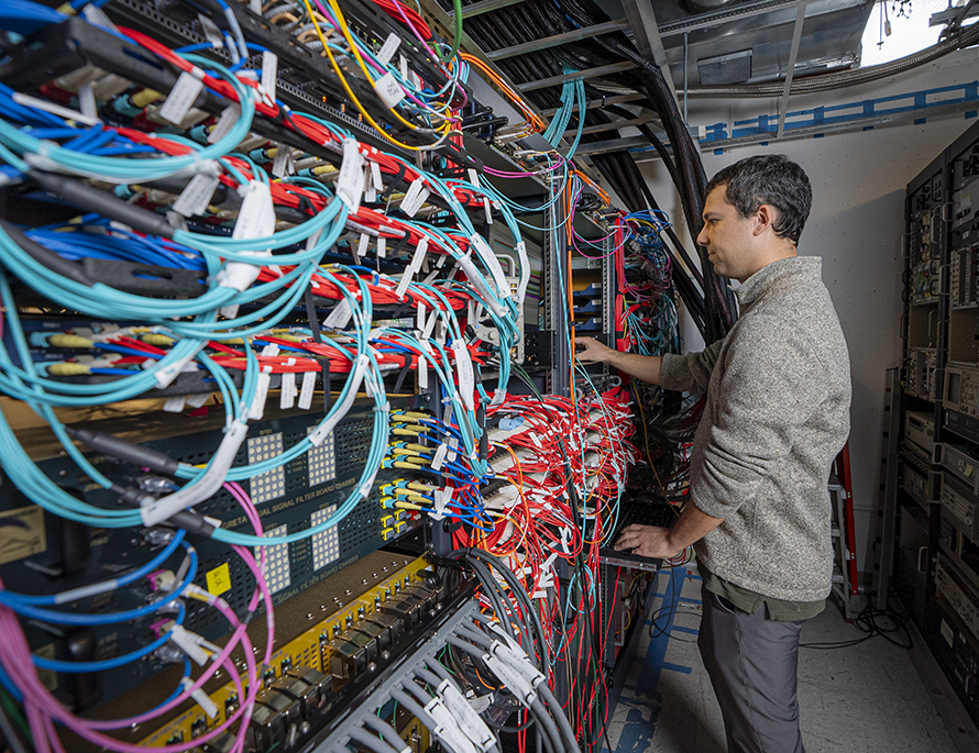 A technician examining equipment on a wire rack.