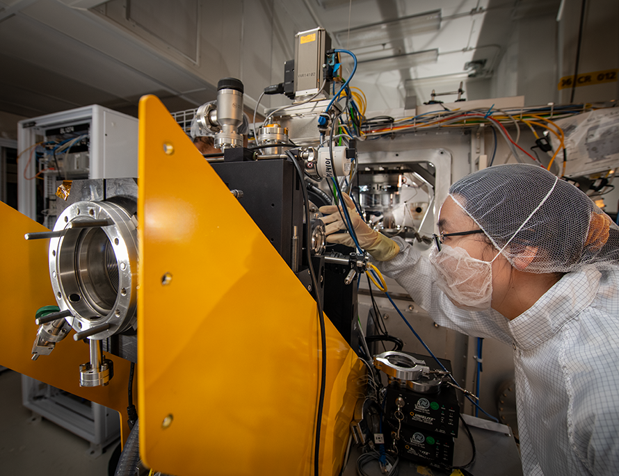 Researcher wearing PPE operating on precision scientific apparatus.