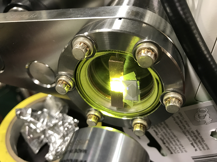 Close up view of a COSMIC component with a green beam visible.