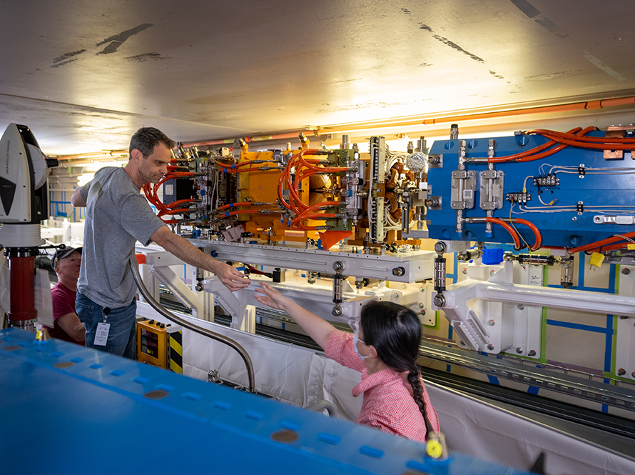 Three engineers working together, with one handing a component to another.