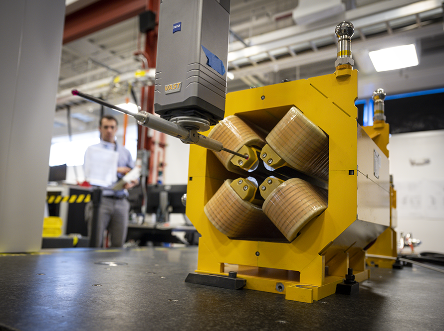 Yellow metallic equipment in the foreground, with a researcher in the back.