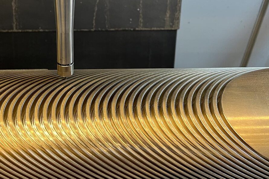 A computer numerical control (CNC) machine in Berkeley Lab Engineering’s Building 77 traces the intricate groove pattern for a superconducting cable into an aluminum-bronze mandrel.