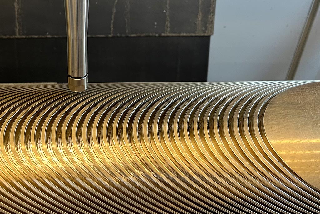 A computer numerical control (CNC) machine in Berkeley Lab Engineering’s Building 77 traces the intricate groove pattern for a superconducting cable into an aluminum-bronze mandrel.