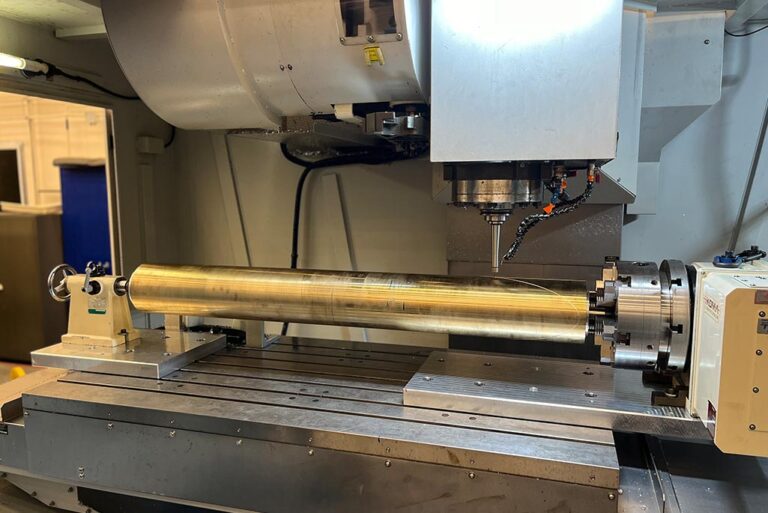 An aluminum-bronze mandrel blank sits in the CNC machine during the early stages of the milling process.