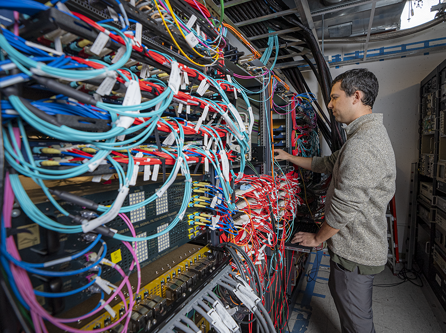 man working at wall of wires for super computer