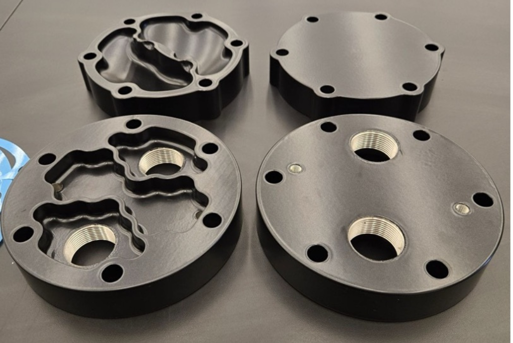 A close up of four brand-new powder-coated chiller end bells sit on a black background.