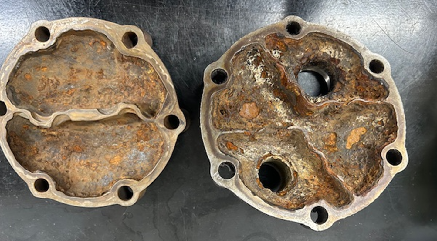 Two rusted out pump heads sit side by side on a black background.