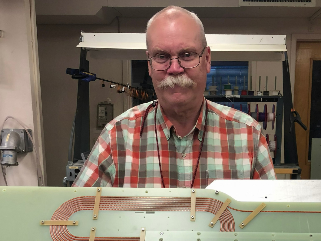 Jim Swanson holds up a racetrack magnet that is part of a high-temperature superconducting magnet comparison project.