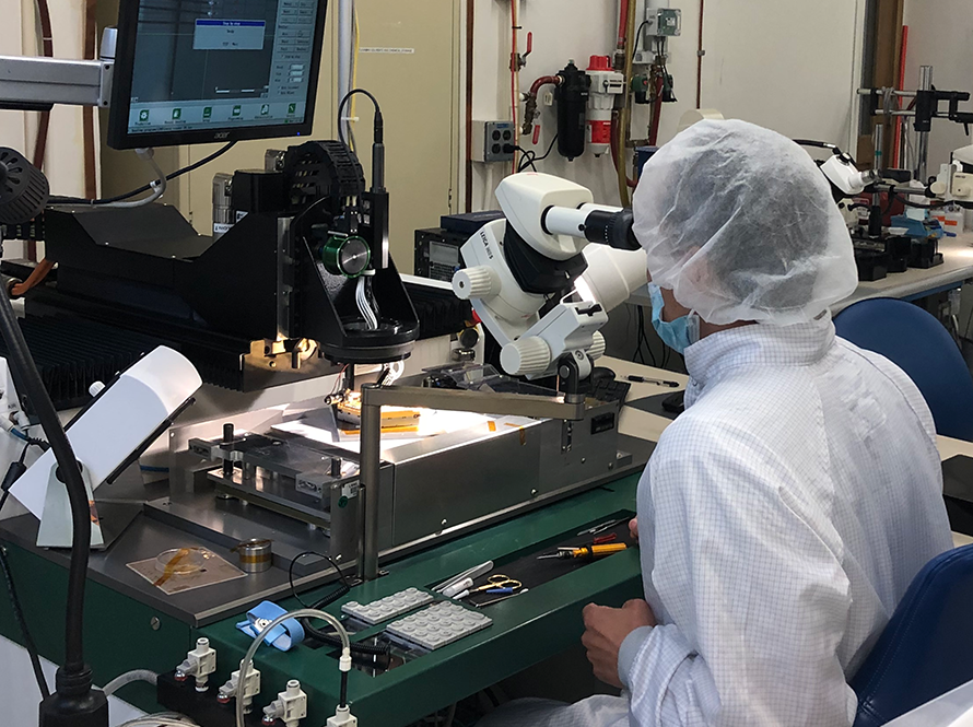 Phathakone Sanethavong looks through a microscope while working on wire bonding a wafer for a cosmic microwave background project for the Physics Division.