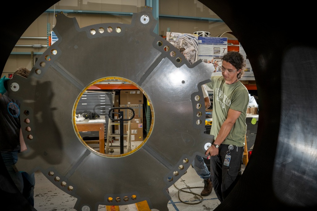 Mechanical Technician Marcos Toledo McGee lifts a component of the ATLAS Detector carbon fiber cylinder into place in the Engineering Division’s shop facility.