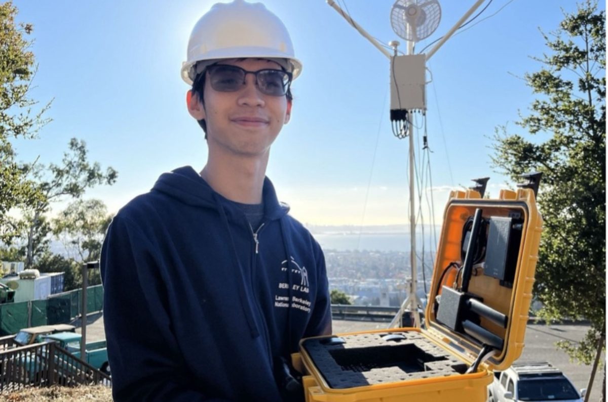 Howard Yao holding the mobile test unit at the research site.