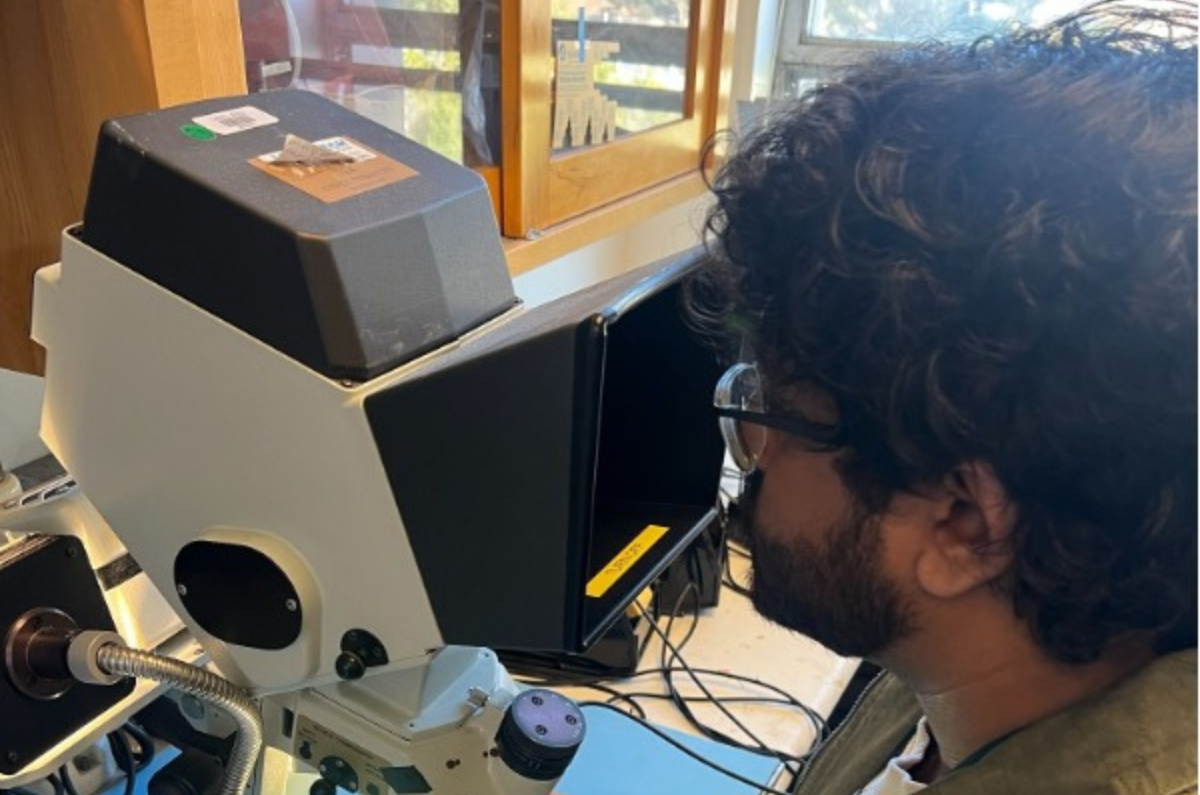 Om Aggarwal looking through a microscope to solder a Printed Circuit Board.